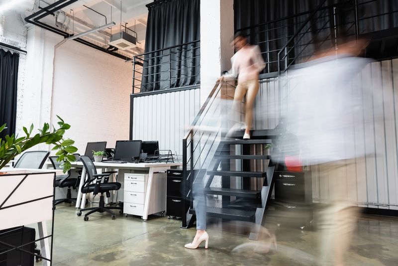 VistaCreate 423884910 stock photo motion blur businesswomen businessman walking modern office computers